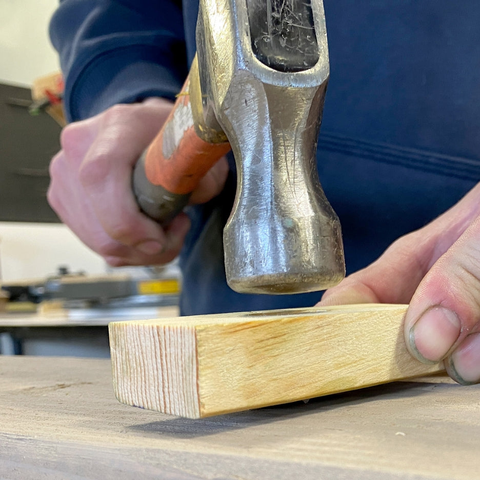 Hands holding hammer and wood piece