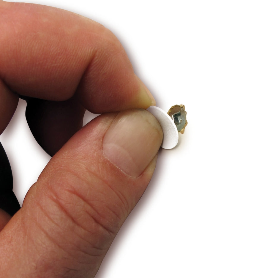 Hand placing FastCap self-adhesive screw cap cover over screw hole