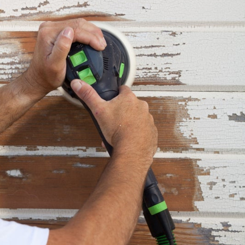 Person using Festool 100Y Multi-Mode Rotex Sander 150 on a wooden wall