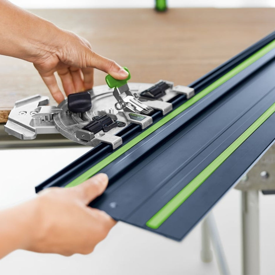 Hands holding a Festool quick-action clamp, with the thumb pressing down on the handle to secure the clamp to the guide rail.