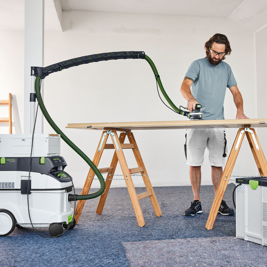 Man sanding door with Festool Boom Arm Set on top of CT 36 dust extractor with hose suspended over the workpiece