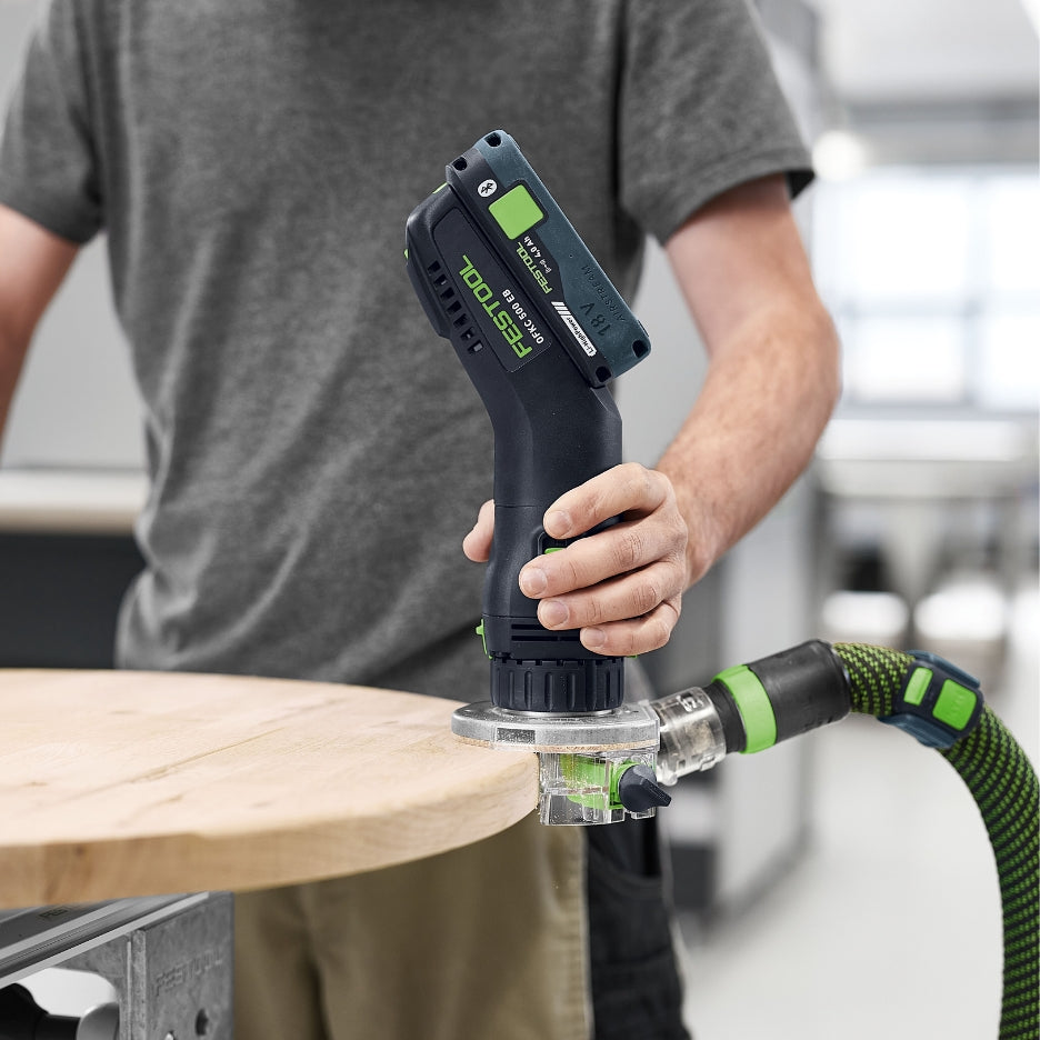Person using Festool Cordless Edge Trimming Router OFKC 500 R3 EB-Basic on a wooden surface with a blurred background