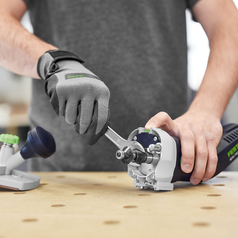 A close-up view of a person using a wrench to change the router bit on the Festool MFKC 700 EB edge trimmer