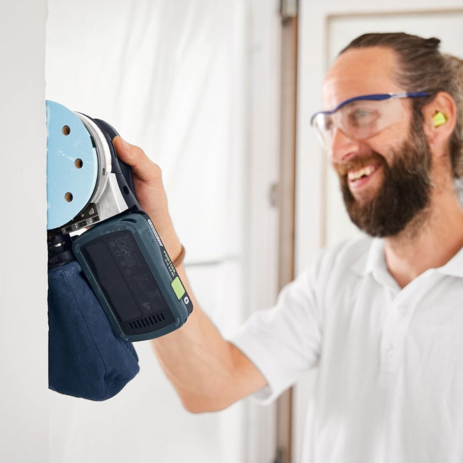 Man sanding wall using Festool ETSC 2 125 with dust bag