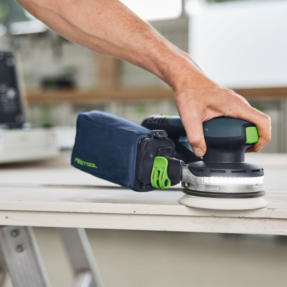 Hand holding Festool ETSC 2 125 with dust bag attached