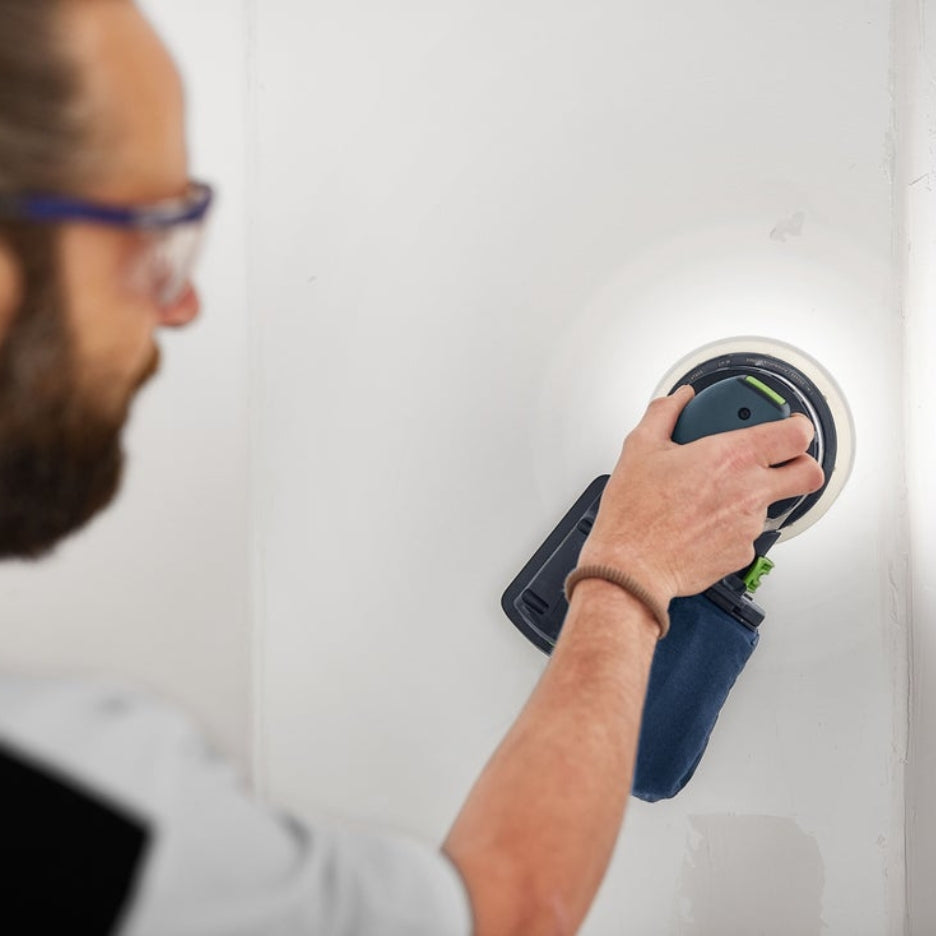 Look from behind of man sanding wall using ETSC 2 150