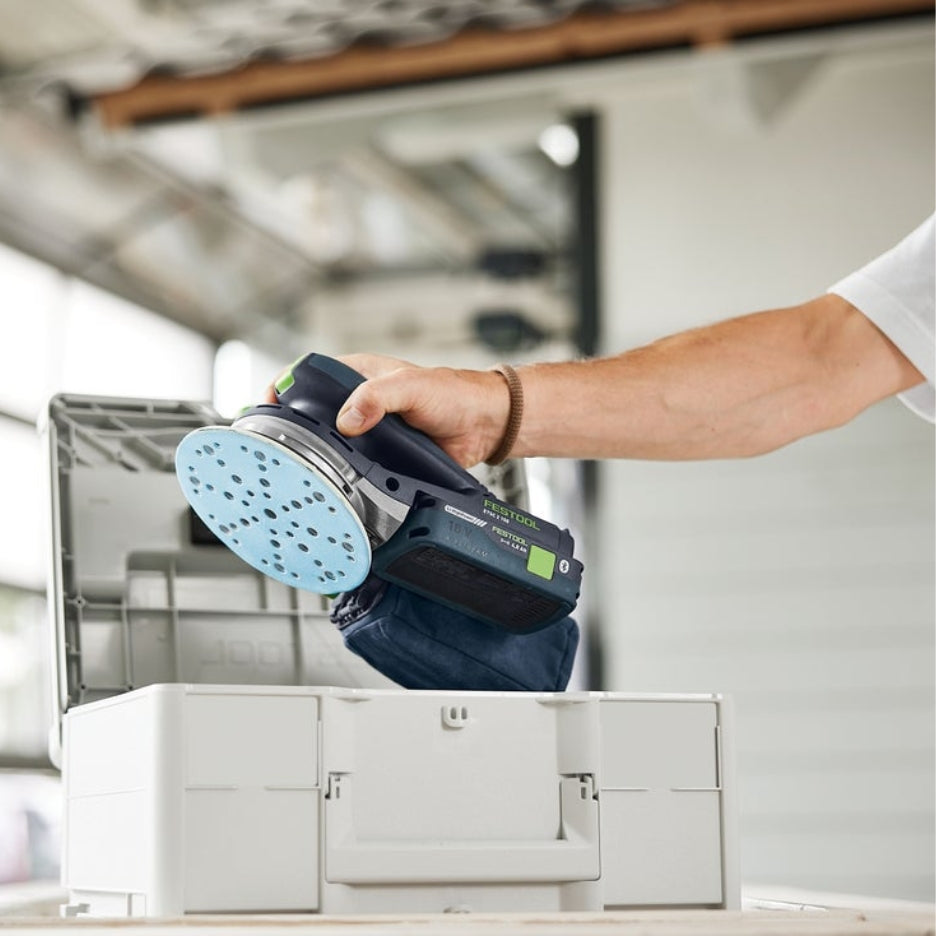 Hand holding Festool ETSC 2 150 with Granat abrasive and dust bag close to Systainer