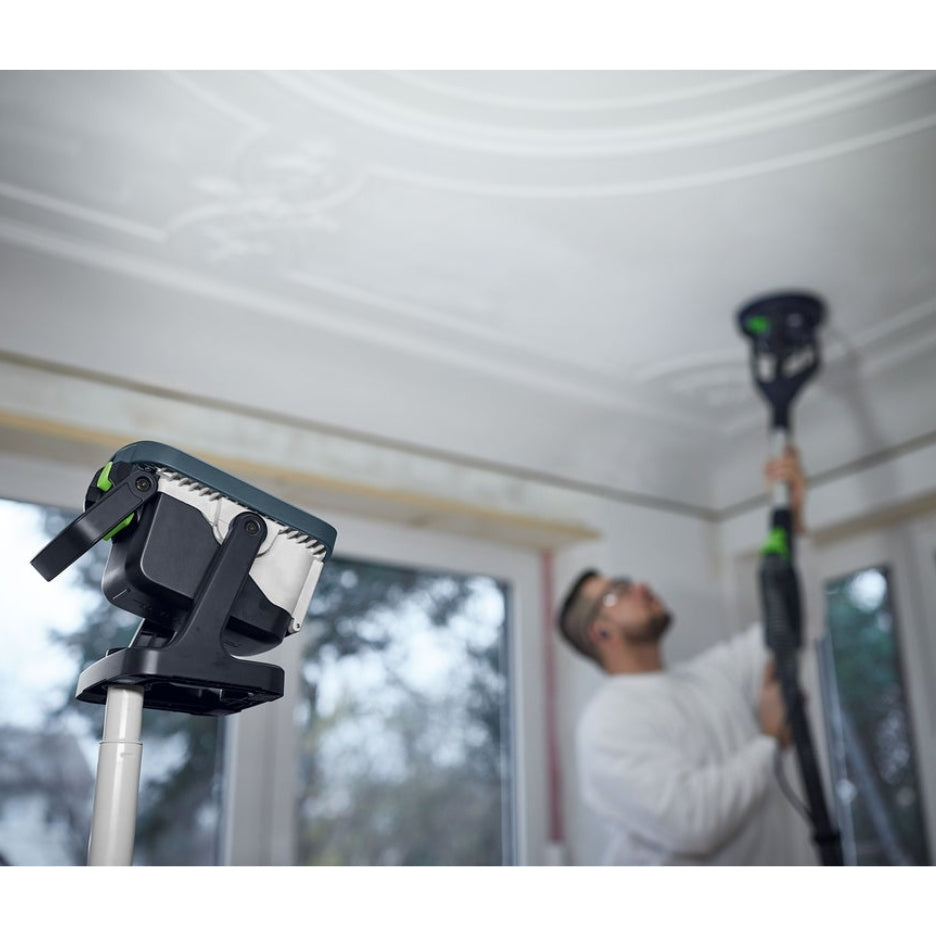 Festool Cordless Site Light SYSLITE KBS C on pole, illuminating man sanding the ceiling