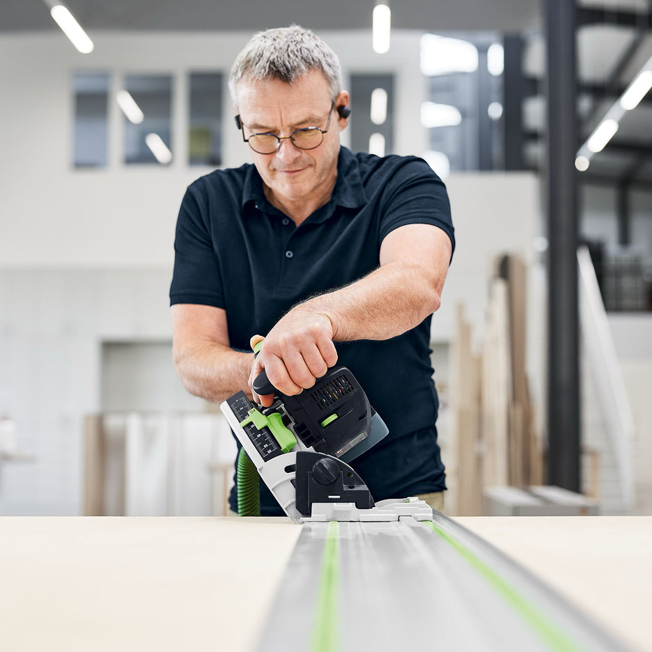 Man uses Festool TSC 55 KS on a guide rail to make a bevelled cut on a sheet of white melamine.