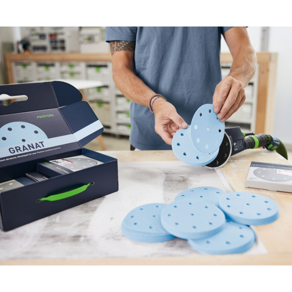 Man holding Festool Granat 5 Inch Abrasive discs close to sander