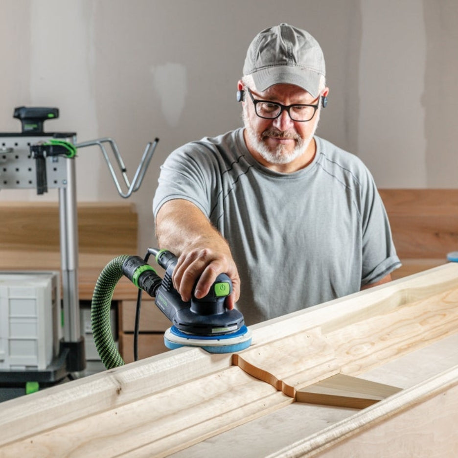 Man sanding a wooden mantel using a Festool sander and Festool Grit Abrasives Granat PROfile D150 M GR PRO