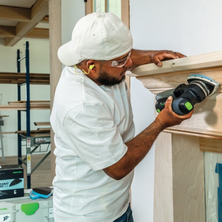 Man sanding fireplace mantel using cordless Festool sander with Festool Grit Abrasives Granat PROfile Delta M GR PRO