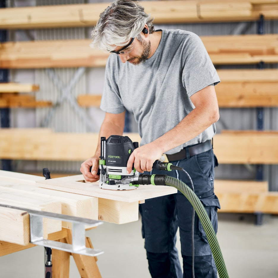Man using Festool Plunge Router OF 1400 EQ-F-Plus on a wooden surface in a workshop setting