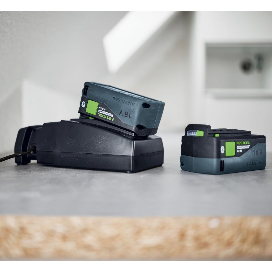 Festool battery and charger on a concrete surface with a blurred background