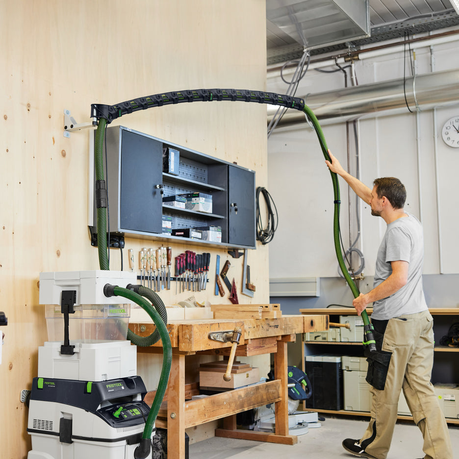 Man swivels Festool Wall-Mount Boom Arm Set out of the way, against the wall over top of his workbench and storage cabinet.