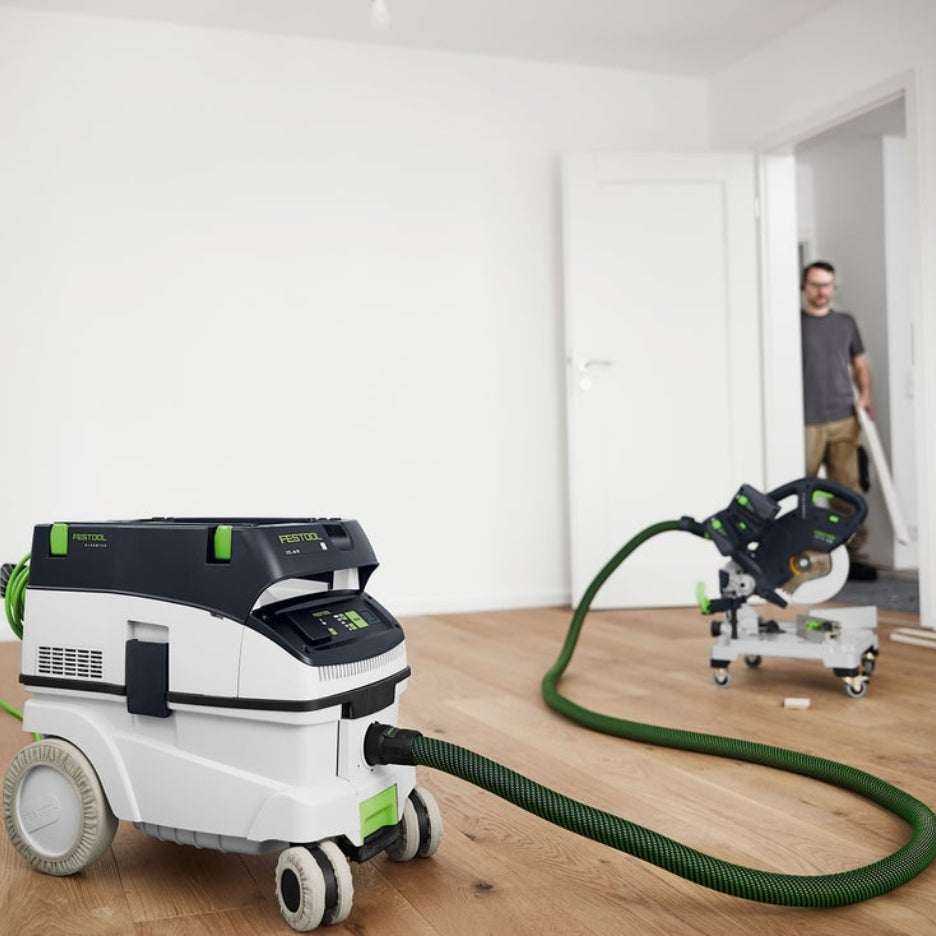 Dust extractor with wheel covers and track saw in the background