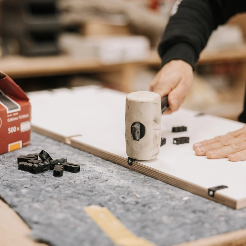Person using mallet to insert Lamello Cabineo 8 M6 into grooves in piece of wood