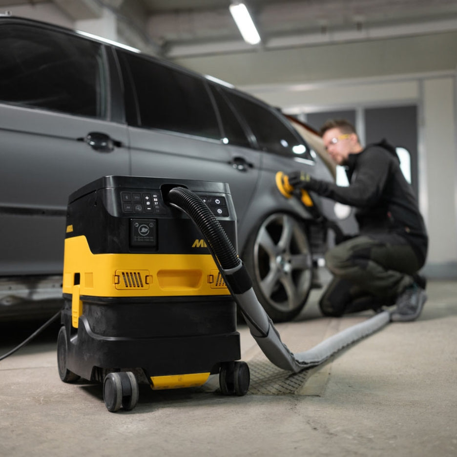 Person using a Mikra sander attached to Mirka DEXOS 17 Litre Dust Extractor 1217X to sand a car