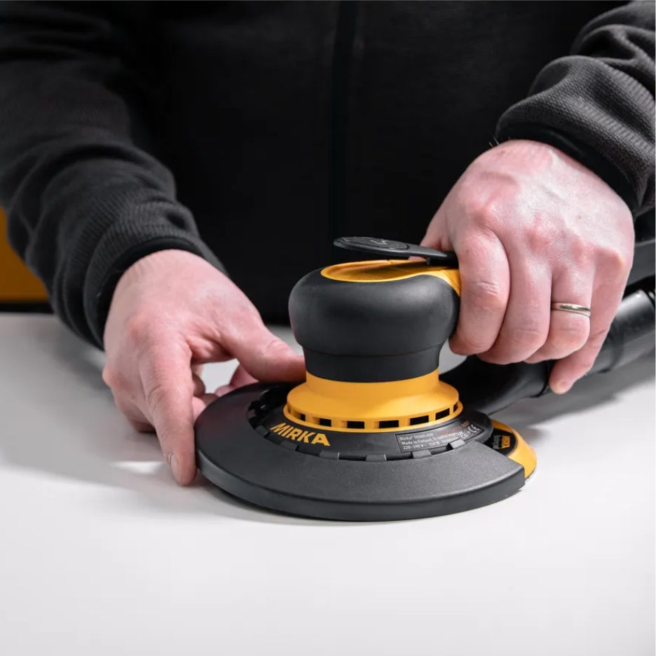 Person attaching Mirka Edge Protector to DEROS sander
