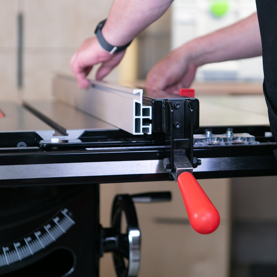 Person adjusting the fence on a table saw, with hands placing a metal guide.