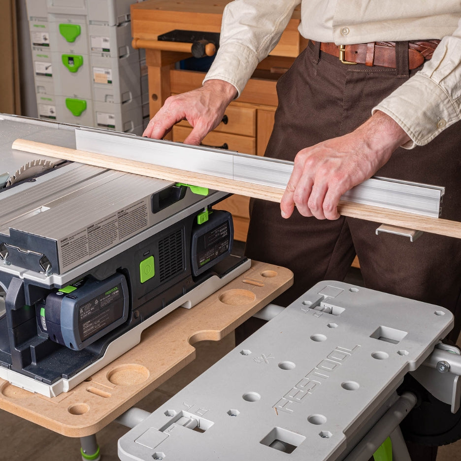 Person using the TSO Products Extended Miter Fence on the Festool CSC SYS 50 to guide a wood strip through the blade for a rip cut.