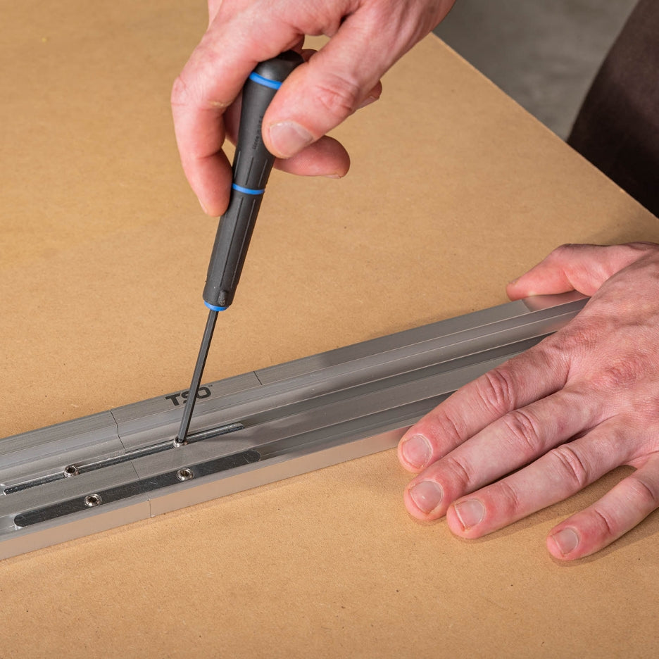 Hands tightening screws using a screwdriver on TSO Products Extended Miter Fence