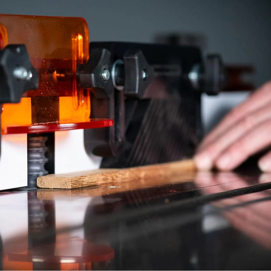 Close-up of a router with UJK Tools Router Bit in operation with a hand holding a wooden piece