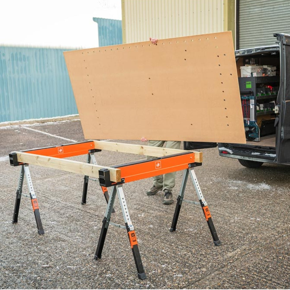 UJK Tools Sawhorses with a large sheet of MDF on top, outdoors near a truck.