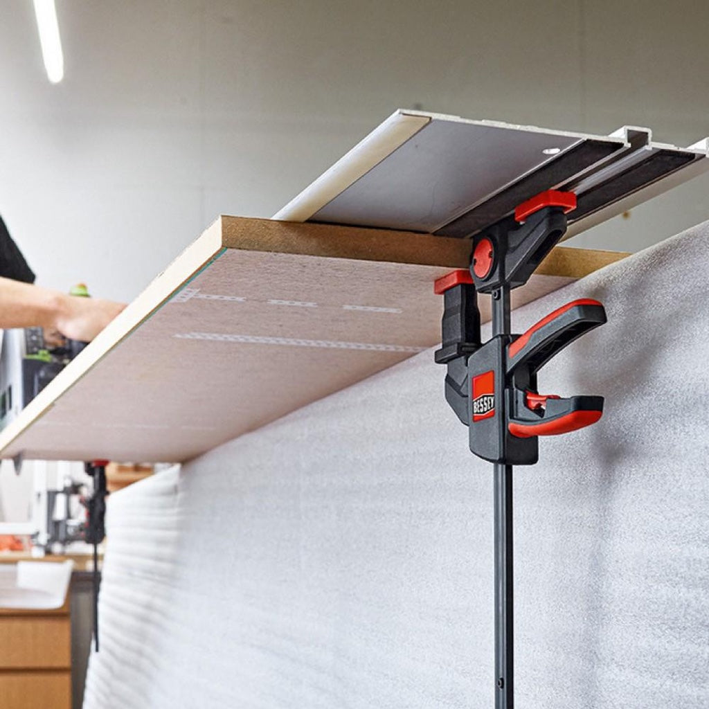 Bessey EZR clamps w/ stepover attachment attached to a Festool guide rail clamped to a MDF panel for cutting with track saw.