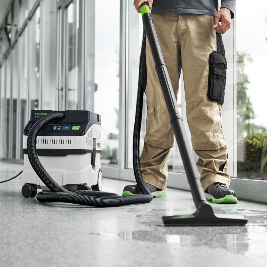 A worker uses the CT 15 with accessory floor sweep to clean up water on the floor.