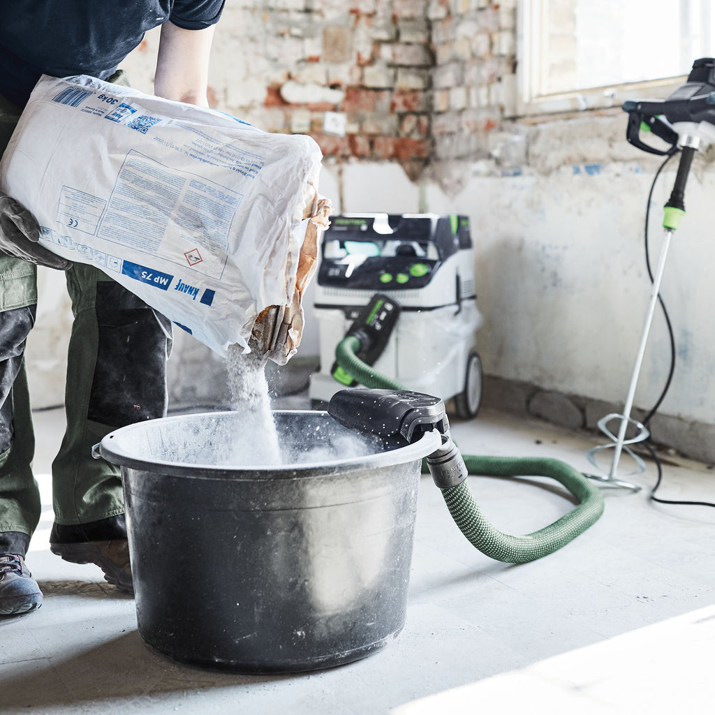The dust extraction bucket accessory is clipped onto a bucket while a worker pours a fine white material to be mixed.