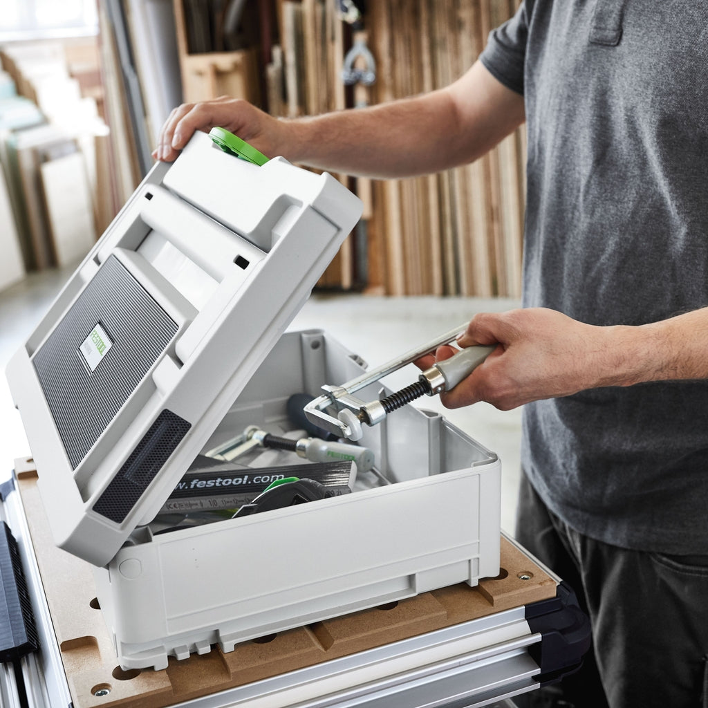 A worker fills the bottom of his Festool TopRock Bluetooth Speaker with clamps, safety glasses, and other accessories.