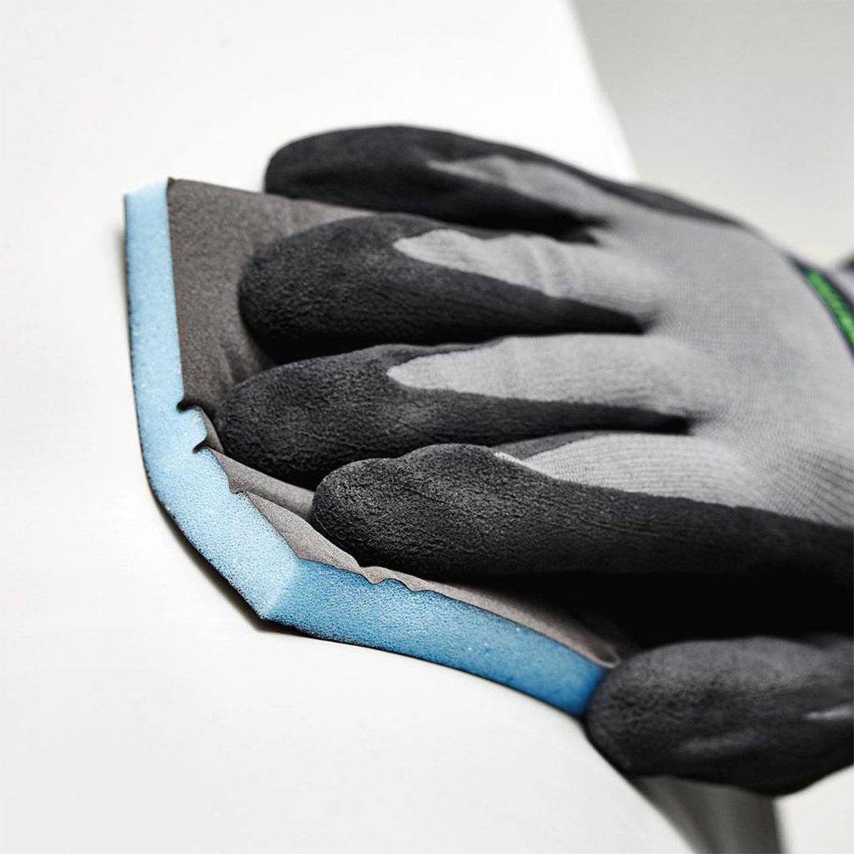 A gloved hand presses an abrasive sponge into a concave surface and the foam distributes the pressure evenly.