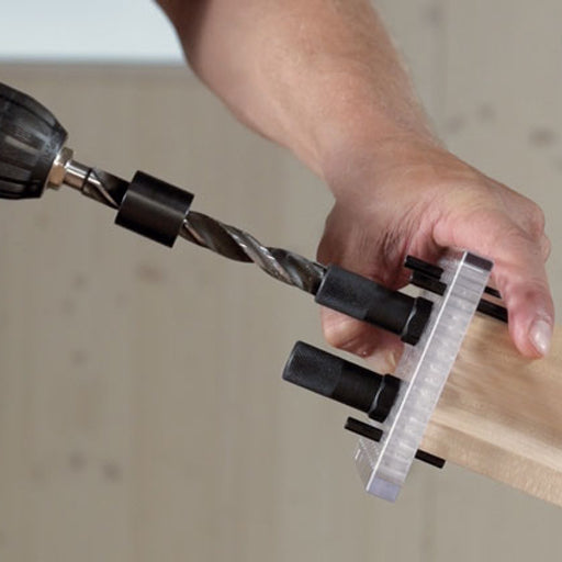 Man holds Lamello Rasto Duo jig on the end of a handrail while drilling for Invis Mx2 hardware with drill bit & bushing.