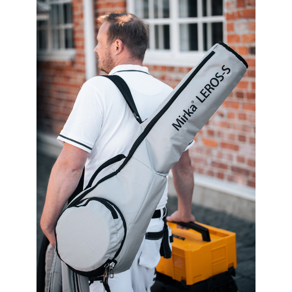 A drywaller has his Mirka LEROS-S drywall sander packed in its bag slung over his shoulder as he walks to his van.