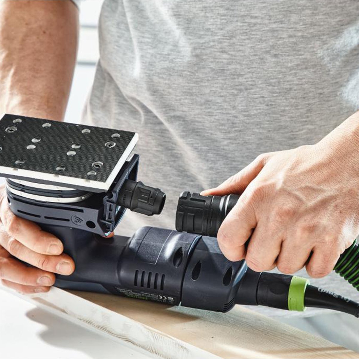 The dust bag is removed and an operator is attaching a dust extractor hose to the RTSC 400 sander.
