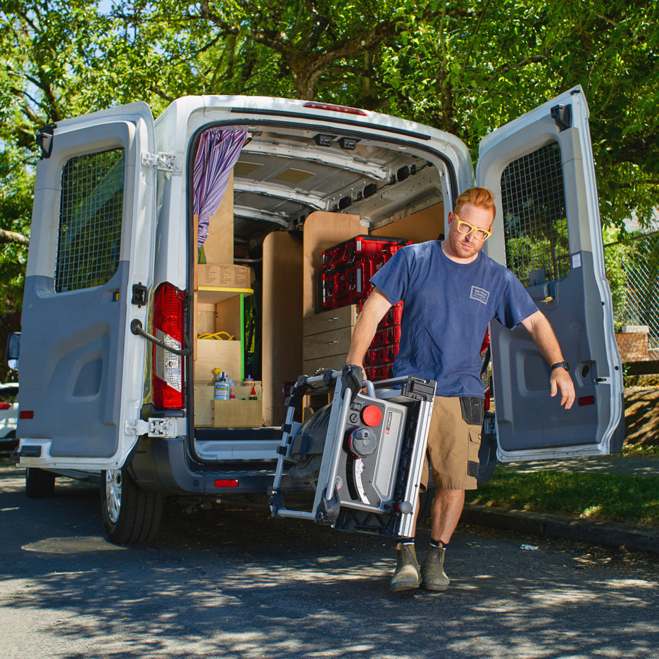 Man carries SawStop Compact Table Saw out of work van with one hand.
