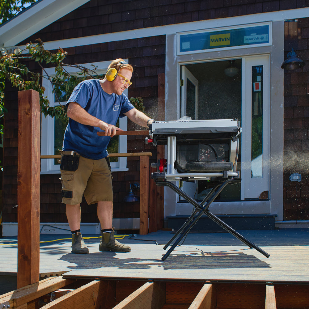 Man rips wood with SawStop Compact Table Saw. Dust flies out back.