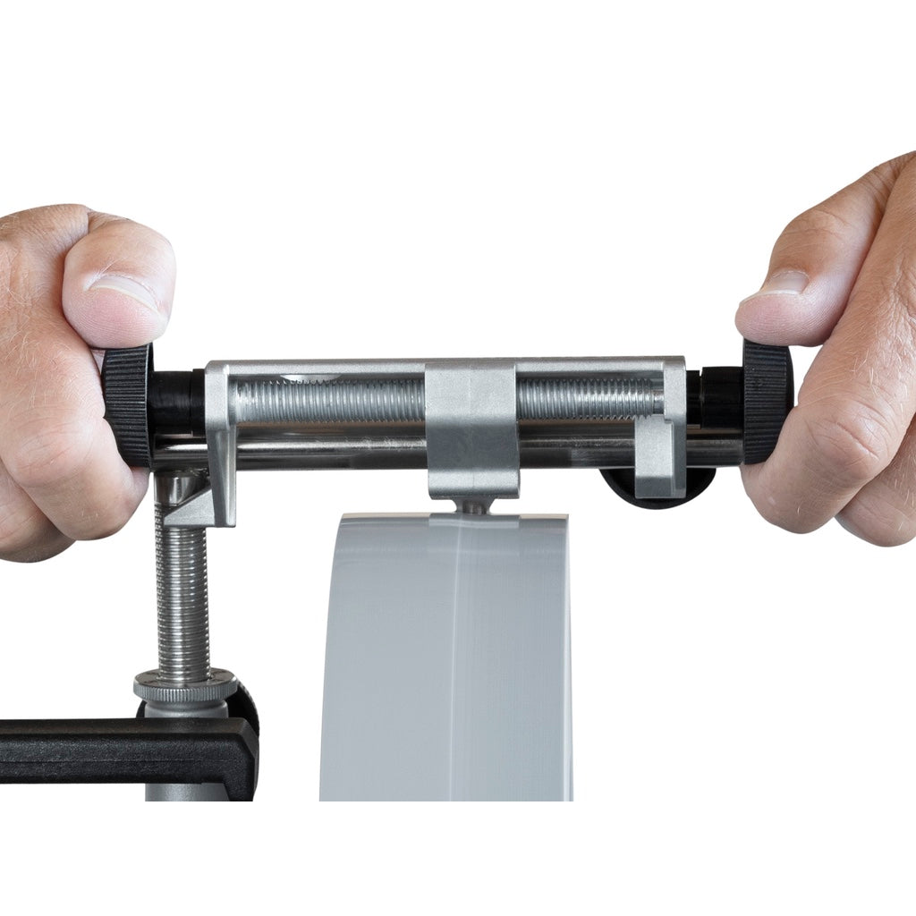 An operator uses the Tormek TT-50 to straighten and flatten the face of a Tormek wet grinding wheel using the side knobs.