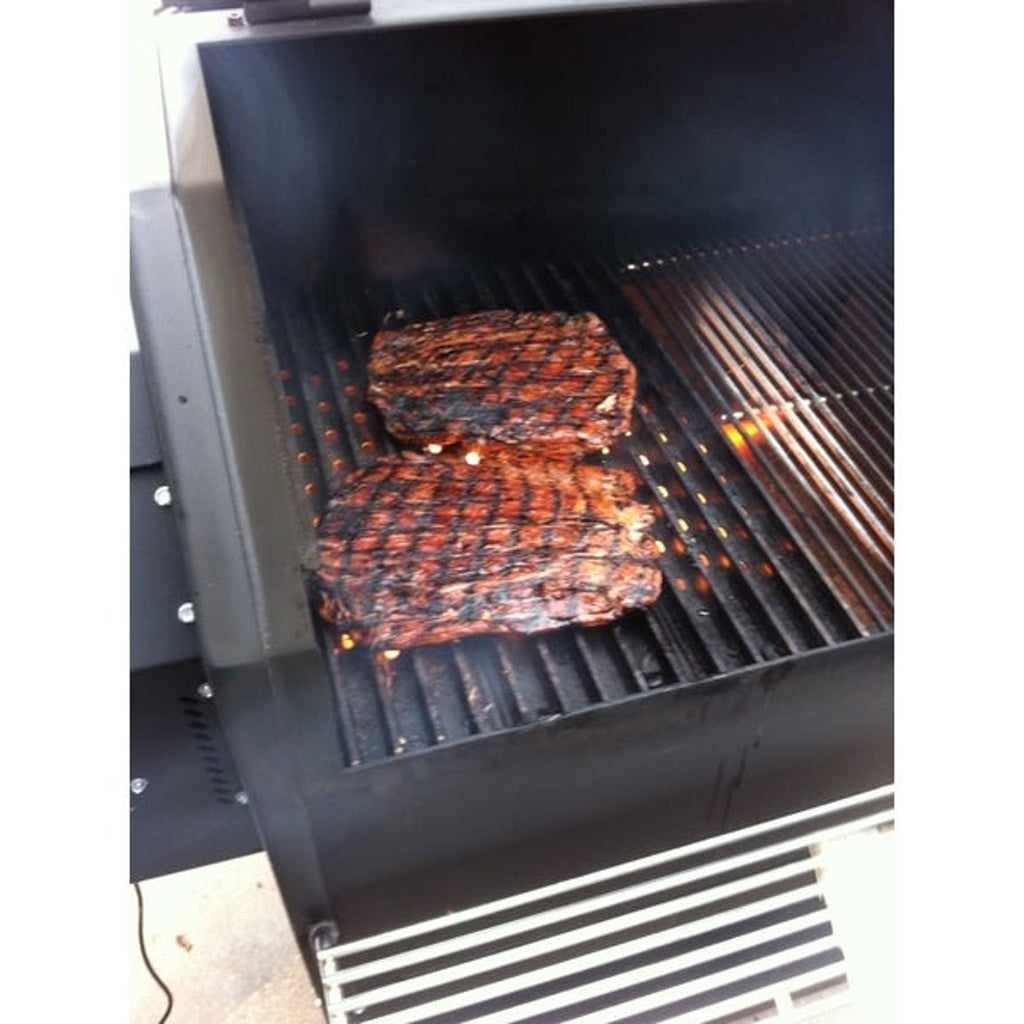 Two steaks with grill marks and beautiful colour being grilled on grill grates on a Yoder Smokers YS640 pellet grill.