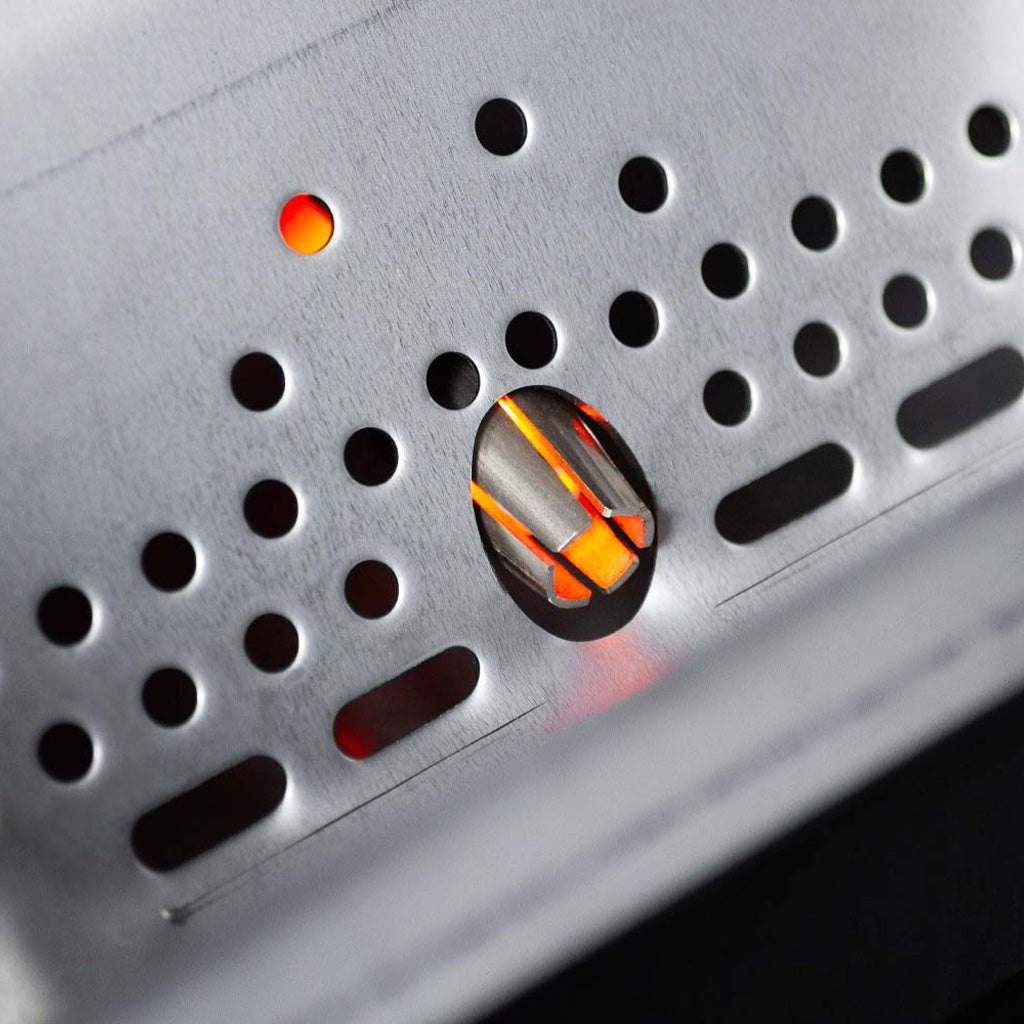 The metal shroud covering the ceramic igniter peeking through the pellet grate.