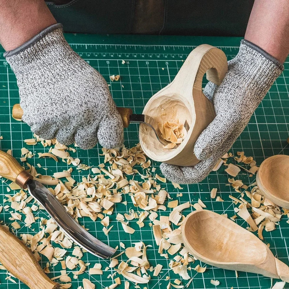 Wooden spoon being carved on a green cutting mat with wood shavings