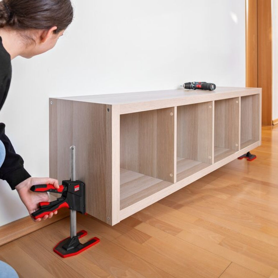 Person levelling a wooden cabinet with two Bessey Tools Beyceps to fasten it to the wall