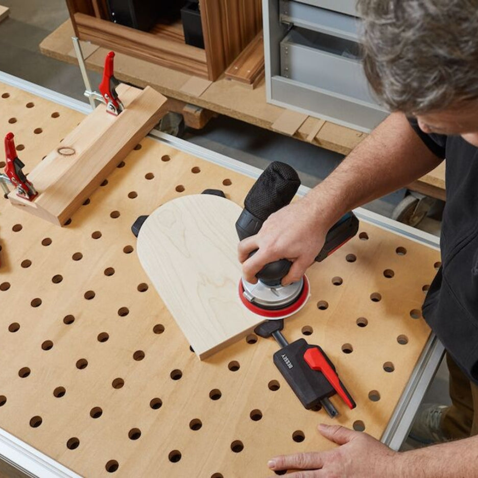 Man sanding work being held with Bessey Tools Horizontal Table Clamp Fixture 