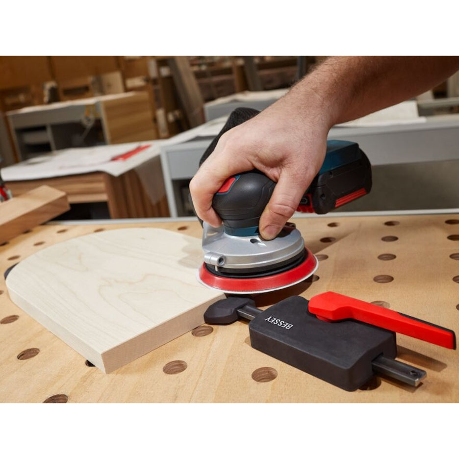 Man sanding work being held with Bessey Tools Horizontal Table Clamp Fixture