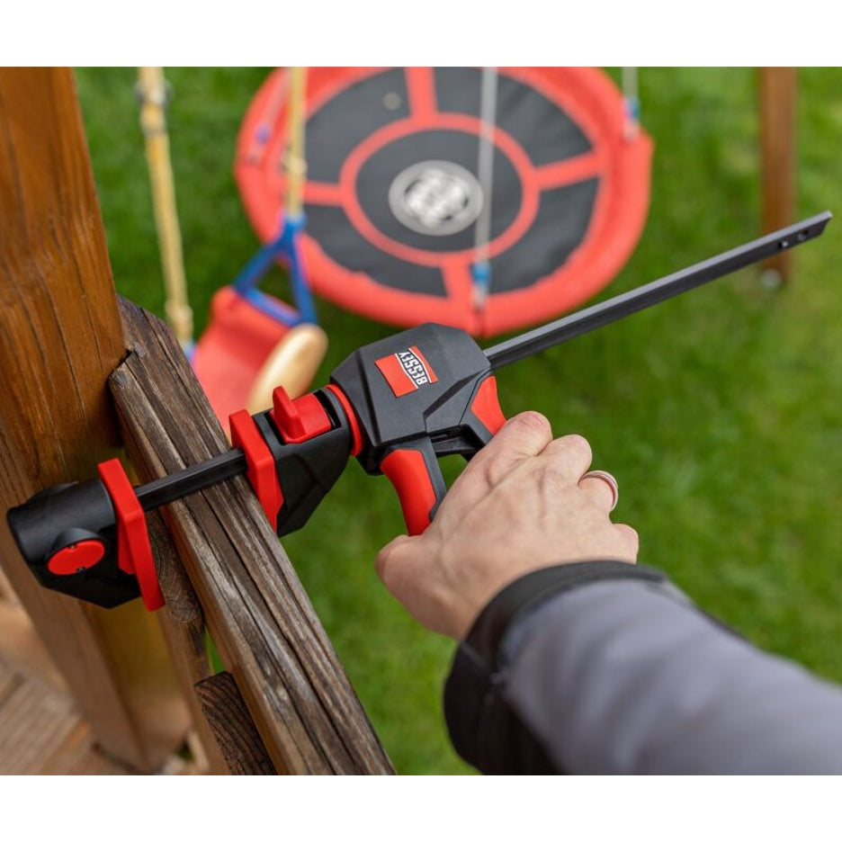 Person using Bessey Tools Trigger Clamps on a wooden structure in the backyard