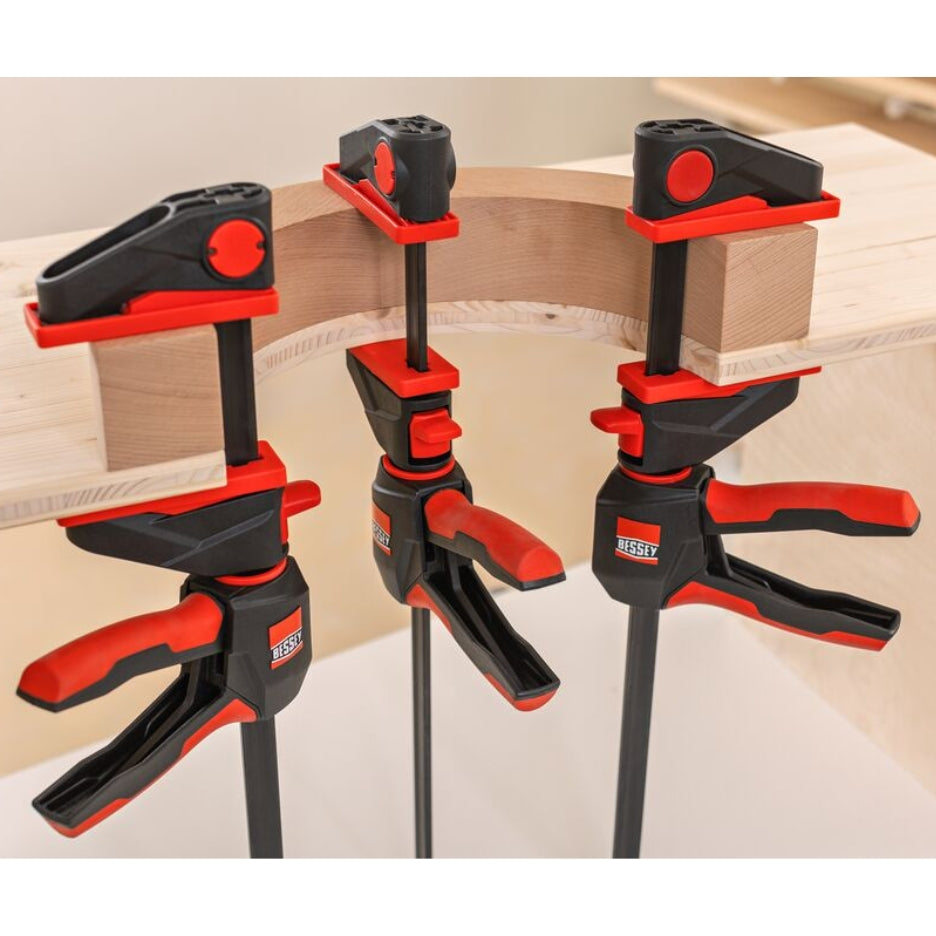 Three Bessey Tools Trigger Clamps holding wooden boards together on a light background