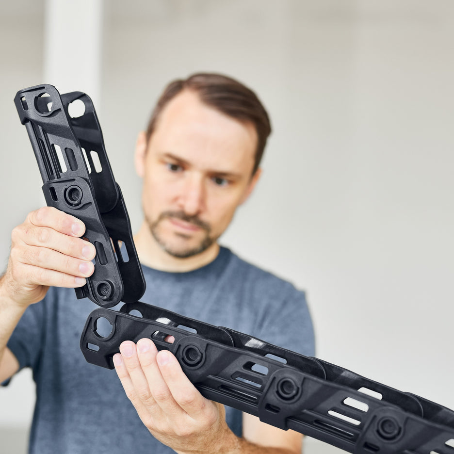 A man installs two Chain Links on a Festool Boom Arm Set.