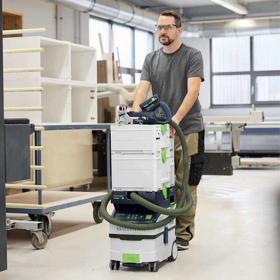 Man transporting Festool Cordless Domino Joiner DFC 500 on top of Systainers and dust extractor 