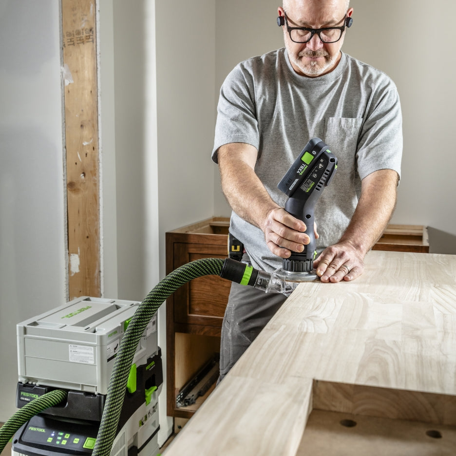 Man using Festool Cordless Edge Trimming Router OFKC 500 R3 EB-Basic on a wooden surface with a workshop background